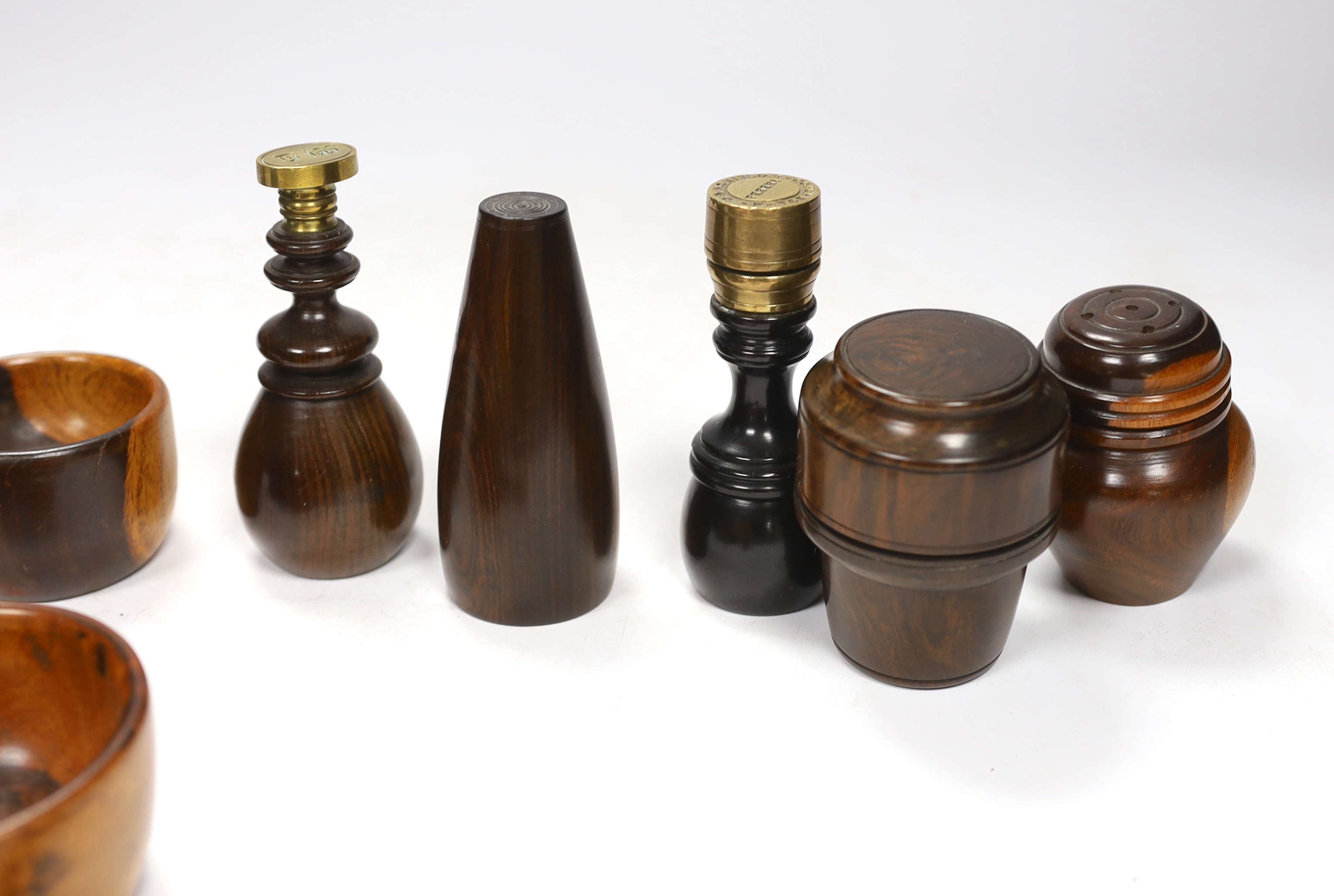 A collection of 19th/20th century lignum vitae vessels and desk items, to include a pepper pot, salt pot, two desk seals, a whistle, a candlestick etc.